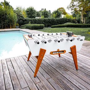 Le baby-foot Stella Outdoor blanc au bord de la piscine – Résiste aux intempéries toute l’année.