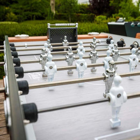 Joueurs chromés et blancs sur barres inox – Baby-foot Stella Outdoor pour parties en extérieur.
