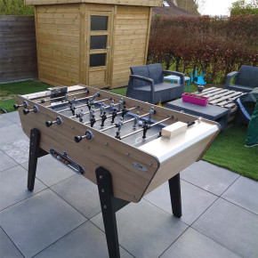 Babyfoot d'extérieur Stella Star effet chêne installé dehors sur une terrasse.